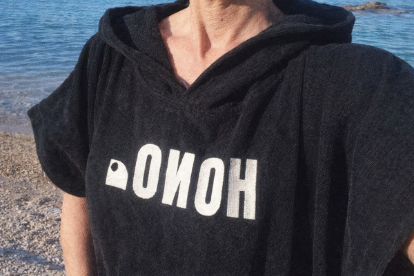 Poncho surf noir HONO porté sur plage, vêtement surf bio en coton absorbant