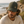 Homme portant une casquette trucker HONO kaki et beige avec logo brodé beige, photographié en bord de mer sur un sentier côtier. Casquette surfwear éco-responsable en coton biologique et polyester recyclé, style premium inspiré de l'univers du surf.
