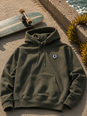 Hoodie à capuche HONO coton bio kaki, sweat surf éco-responsable avec logo poitrine, style surfskate en bord d'océan.