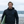 Homme portant veste softshell hiver HONO noire  recyclée au bord de mer avec planche de surf