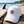 Casquette surf blanche recyclée HONO avec pbroderie tricolore posée sur une table en bois face à l'océan, à côté d'une planche de surf, dans une ambiance bord de mer lumineuse