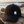 Casquette surf recyclée HONO Wave noire avec logo brodé blanc, photographiée sur du bois flotté face à l'océan dans une ambiance bord de mer