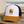 Casquette surf trucker recyclée HONO avec logo brodé camel, panneau avant blanc, visière camel et arrière en mesh navy recyclé, photographiée sur une table en bois face à l'océan.