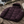 Doudoune chaude en nylon recyclé HONO Surfwear bordeaux posée sur une terrasse en bois face à l’océan
