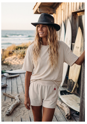Ensemble surf femme HONO ivoire avec t-shirt et short en coton biologique en bord de mer