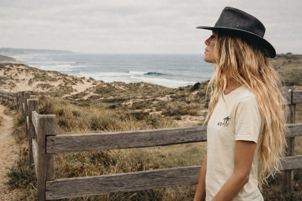 femme en bord de mer portant un t-shirt HONO surfwear beige regardant l’océan ambiance surf lifestyle nature