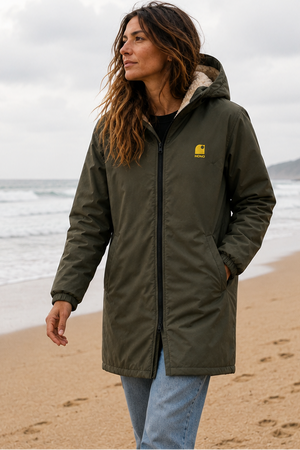 Imperméable surfkaki HONO doublé polaire avec capuche et broderie jaune, porté par une femme sur la plage, surfwear bio écoresponsable et marque surf française