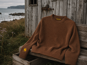 Pull HONO Surf Coastlife homme Toffee en coton bio et polyester recyclé posé sur un banc en bord de mer
