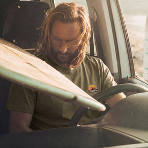 surfeur dans un van portant un t-shirt HONO surfwear kaki avec planche de surf style lifestyle surf vintage