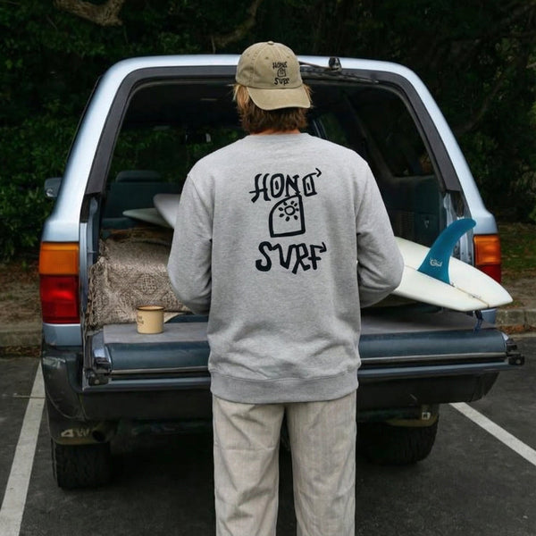 Sweat gris HONO Surf pour homme, surfwear durable, porté en lifestyle surf devant un van avec planche de surf.